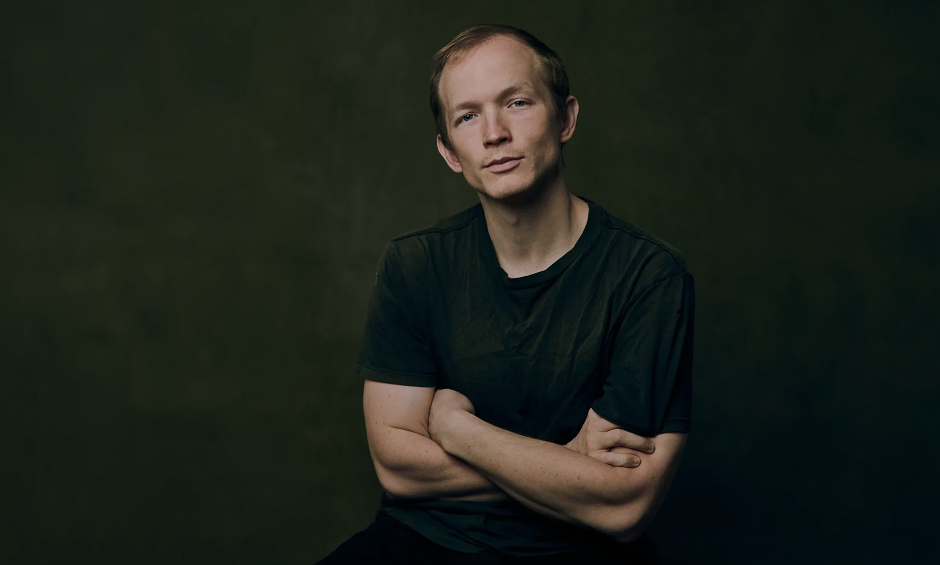 Individual seated, contemplative expression, moody lighting